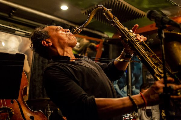 Jay Rodriguez bending back while playing tenor saxophone